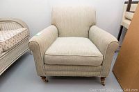 Front view of the beige upholstered Elte chair showing full seat cushion and armrests.