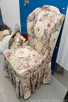 Side view of the floral wingback chair showing fabric pattern and pleated skirt detail