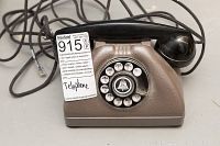 Close-up photo of the vintage Bell System rotary dial telephone showing the rotary dial with numbers and letters, the brown base, and black handset, with an attached phone cord ending in a modern phone jack.