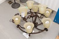 Full view of the bronze metal multi-light fixture with eight frosted amber glass shades arranged in two tiers.