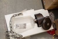 Close up of one Kitchler light showing metal fixture and glass shade with hanging chain in styrofoam