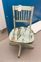 Front view of the distressed wood swivel desk chair showing round seat and slatted backrest.