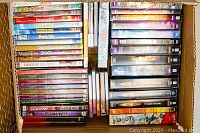 Top-down view of a box filled with DVDs including VeggieTales, The Lion King 1.5, and various others, along with several computer games.
