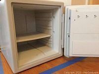 Open view of the interior of the safe showing a shelf and light-colored interior.