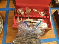 Red-lined chest open showing fitted slots with forks, spoons, knives and bagged pieces in front