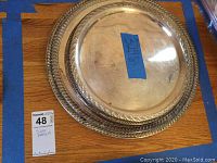 Photo of three stacked silver or silver-type round trays/plates showing braided decorative edges, some tarnish and wear.