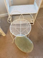 White wicker stool with green cushion and part of a white wicker shelf visible behind