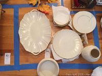 Full view of china set including the serving platter, serving bowl, plates, and saucers arranged on wooden surface