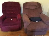 Front view of two upholstered recliners, red and brown, placed side by side on wooden flooring.