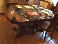 Full view of the large rectangular vintage Thomasville dining table showing the wooden top with some items placed on it and the chairs around it.
