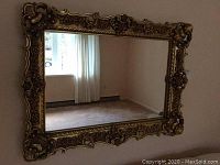 Full view of the rectangular mirror mounted on wall showing the entire ornate gold frame