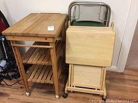 Full view of butcher block island, TV trays with stand, and metal folding chairs leaning against wall