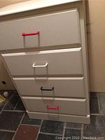 Front view of white dresser with four drawers and red, white, blue, red handles.