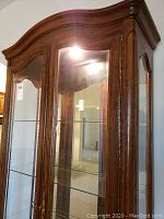 Photo showing the top and front curved doors with glass panes, wood frame, and interior light on.