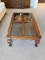 Top-down view of the rectangular coffee table showing four rectangular tinted glass panels within the wooden frame, carpet floor beneath.