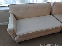Front view of one white upholstered mid-century modern loveseat showing tufted back, seat cushion, arm detail, and tapered legs.