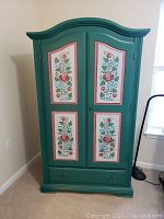 Front view of cabinet with closed doors showing arched top and floral panels
