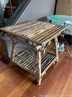 Wooden end table made from natural branches showing rustic slatted top and lower shelf