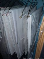 Closely folded white table linens hung on hangers, showing smooth fabric and neat arrangement.