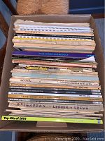Top view of box filled with assorted sheet music books and collections, showing variety and condition.
