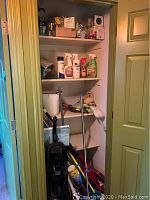 Closet shelves with cleaning supplies including sprays and light bulbs; vacuums and cleaning tools visible on the floor.
