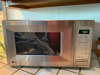 Front view of LG stainless steel microwave oven showing door, window, control panel with display and buttons