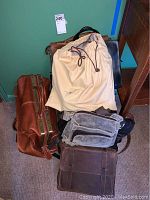 Photo showing all four bags stacked on the floor, colors include brown, black, beige and gray, various sizes and materials.
