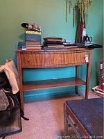 Wooden credenza placed against a teal wall with books and decorative items on top, showing front and side views.