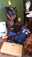 Photo showing the assembled set of camping gear with tent bag, backpack, rope coiled, stove case, and other gear on the floor