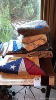 Photo showing folded blankets, a flag with a white star, and part of a platter underneath them on a table.