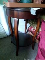 Photo of wooden side table showing curved legs and lower shelf