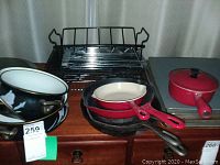 Photo showing various Le Creuset cast iron cookware including frying pans and saucepan, cast iron pans, and enamel pots.