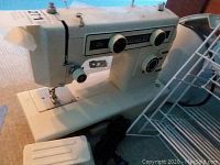 Kenmore 101 sewing machine with foot pedal and white metal wire racks beside it