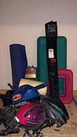 Photo showing all sporting equipment together including yoga mat, step platforms, helmets, weights, and locks.