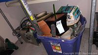 Full lot in large blue plastic bin showing all items inside with gardening tools and ceramic pots