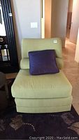 Front view of lime green upholstered chair with purple pillow on seat.