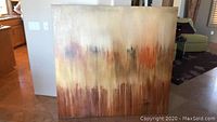 Front view of large abstract art on canvas featuring blended earth tones and vertical color strokes.