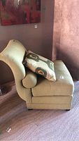 Side view of lime green upholstered chair showing rolled top edge and arm cushions with decorative pillow on seat.