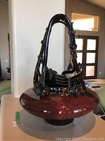 Front view showing reddish-brown speckled wide base and tall black sculptural elements resembling bamboo and boats.