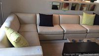Front view of entire beige sectional sofa with pillows