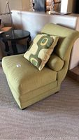 Front angle of lime green armless chair with patterned pillow showing side profile and upholstery texture
