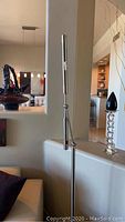 Full view of the chrome floor lamp standing upright near a wall.