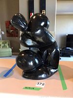 Front angle view of the black abstract modern sculpture statue showing glossy, curvaceous form.