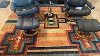 Full view of rug under two leather chairs and ottomans showing overall pattern and size