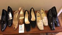 Five pairs of women's shoes size 8.5 narrow arranged side by side on wooden surface