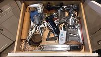 Drawer with assorted kitchenware including graters, rolling pin, knife sharpener, and other utensils