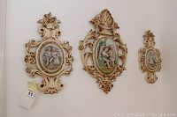 Three wall plaques hanging on a wall, showing relative sizes and arrangement of the lot items.