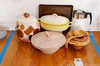 Wide shot of all items including soup tureens, serving bowl, coffee maker, ladle, and wooden tray on wooden floor