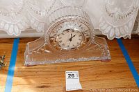 Glass quartz clock in clear cut glass with Roman numeral face and decorative patterns.
