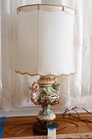 Front view of Capodimonte style table lamp with fabric shade and porcelain base featuring winged figure